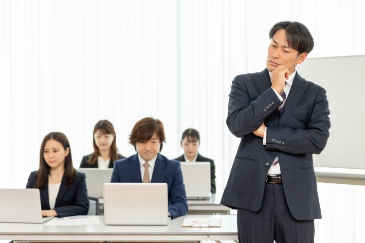 研修の男性講師とスーツ姿の男女（悩む）